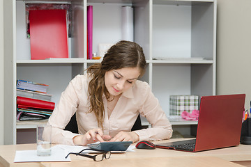 Image showing young girl thinks on the calculator