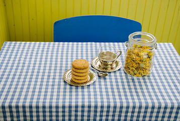 Image showing dried marigold dish with cup and cookies on table 