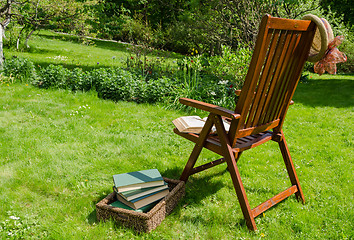 Image showing wooden chair books and hat in garden 
