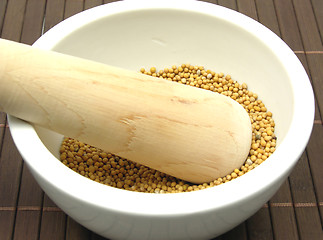 Image showing Pestling grains of mustard seed  in a bowl of chinaware