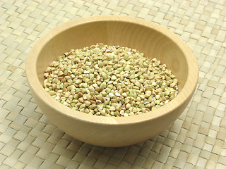 Image showing Wooden bowl with buckwheat on rattan underlay