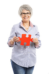 Image showing Elderly woman holding a puzzle piece