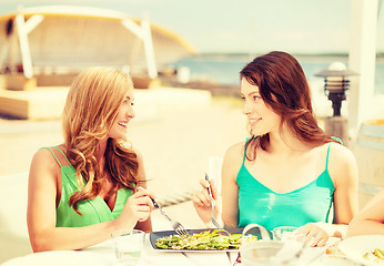 Image showing smiling girls in cafe on the beach