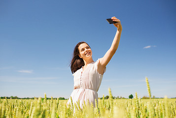 Image showing smiling girl with smartphone on cereal field