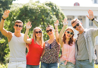 Image showing group of smiling friends waving hands outdoors