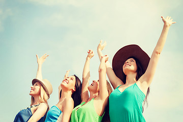 Image showing smiling girls with hands up on the beach