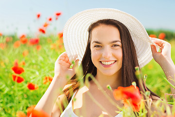 Image showing smiling young woman in straw hat on poppy field