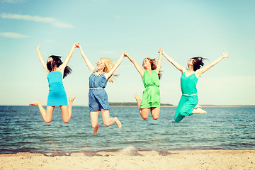 Image showing smiling girls jumping on the beach