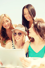 Image showing smiling girls looking at tablet pc in cafe