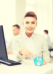 Image showing businesswoman pointing at clock in office