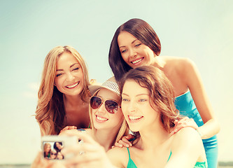 Image showing smiling girls taking photo in cafe on the beach