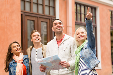 Image showing group of smiling friends with map exploring city