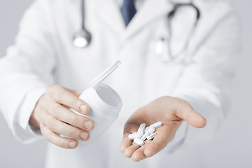 Image showing doctor hands holding white pack and pills