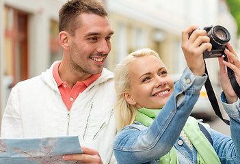 Image showing smiling couple with map and photocamera in city
