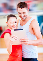 Image showing two smiling people with tablet pc in the gym