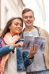 Image showing smiling couple with city guide exploring town