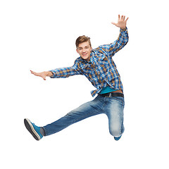 Image showing smiling young man jumping in air