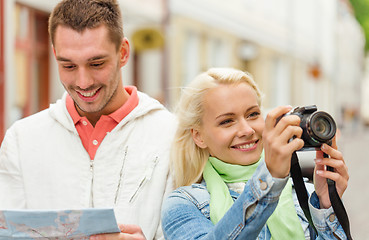 Image showing smiling couple with map and photocamera in city