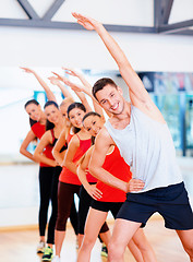 Image showing group of smiling people stretching in the gym