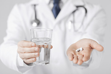 Image showing doctor hands giving white pills and glass of water