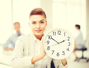 Image showing businesswoman showing white clock in office