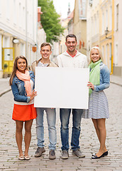 Image showing group of smiling friends with blank white board