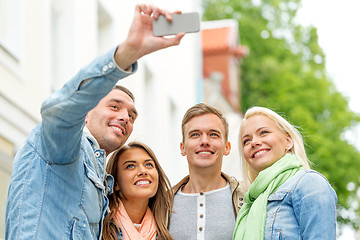 Image showing group of smiling friends making selfie outdoors