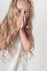 Image showing Little girl covers her mouth with her palms