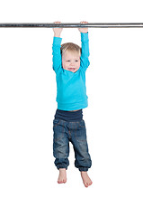 Image showing Portrait of a little boy hangs by horizontal bar