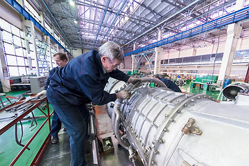 Image showing Mechanics work over assembly of aviation engine