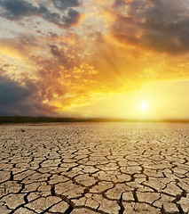 Image showing cracked desert closeup and dramatic sunset over it