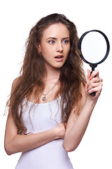 Image showing Surprised woman looking through the magnifying glass