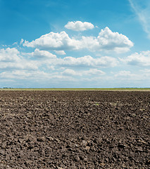 Image showing black arable field after harvesting and blue sky