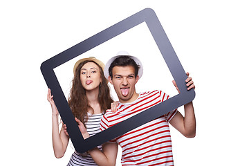 Image showing Happy couple showing tongue through tablet frame