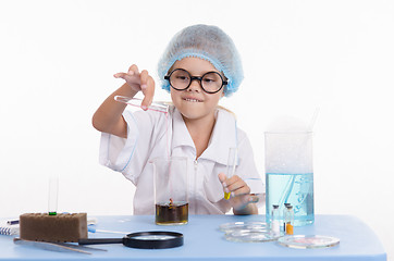 Image showing Chemist pours liquid from test tube into a flask