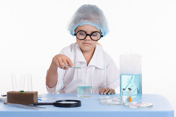 Image showing Girl Chemist pours liquid from a test tube into flask