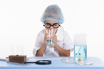 Image showing Chemist smelling contents of the flask