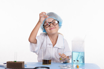 Image showing Girl chemist looking at a liquid in test tube