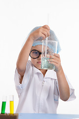 Image showing Girl chemist mixes the contents of flask