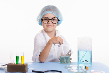 Image showing Chemist sitting at table and prevents liquid in flask