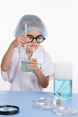 Image showing Girl chemist mixes the contents of flasks