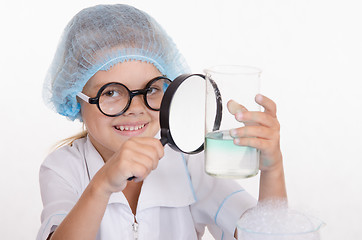 Image showing Chemist examines a flask under magnifying glass