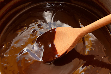 Image showing Melted chocolate being stirred with a wooden spoon