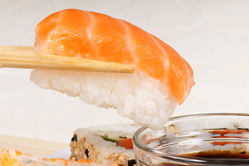 Image showing Chopsticks holding a piece of nigiri sushi