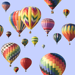 Image showing A group of colorful hot-air balloons floating across a blue sky