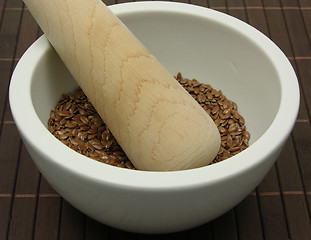 Image showing Pestling brown flaxseed in a bowl of chinaware