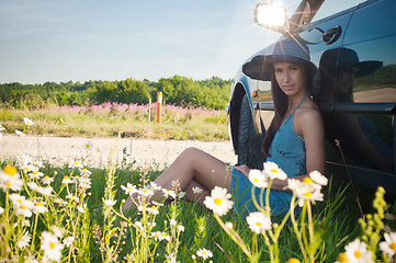 Image showing Young pretty woman sitting near green car