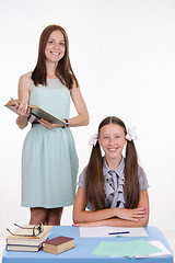 Image showing Pupil at school desk, teacher standing with a book