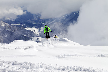 Image showing Freeriders on off-piste slope and mountains in mist