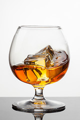 Image showing Splash of whiskey with ice in glass isolated on white background